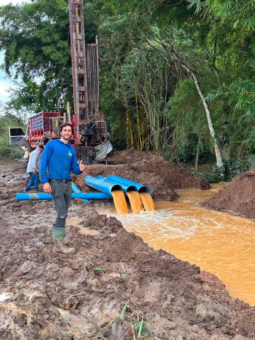 Técnico da Águas Cristalinas na perfuração com forte jato de água saindo dos canos do poço
